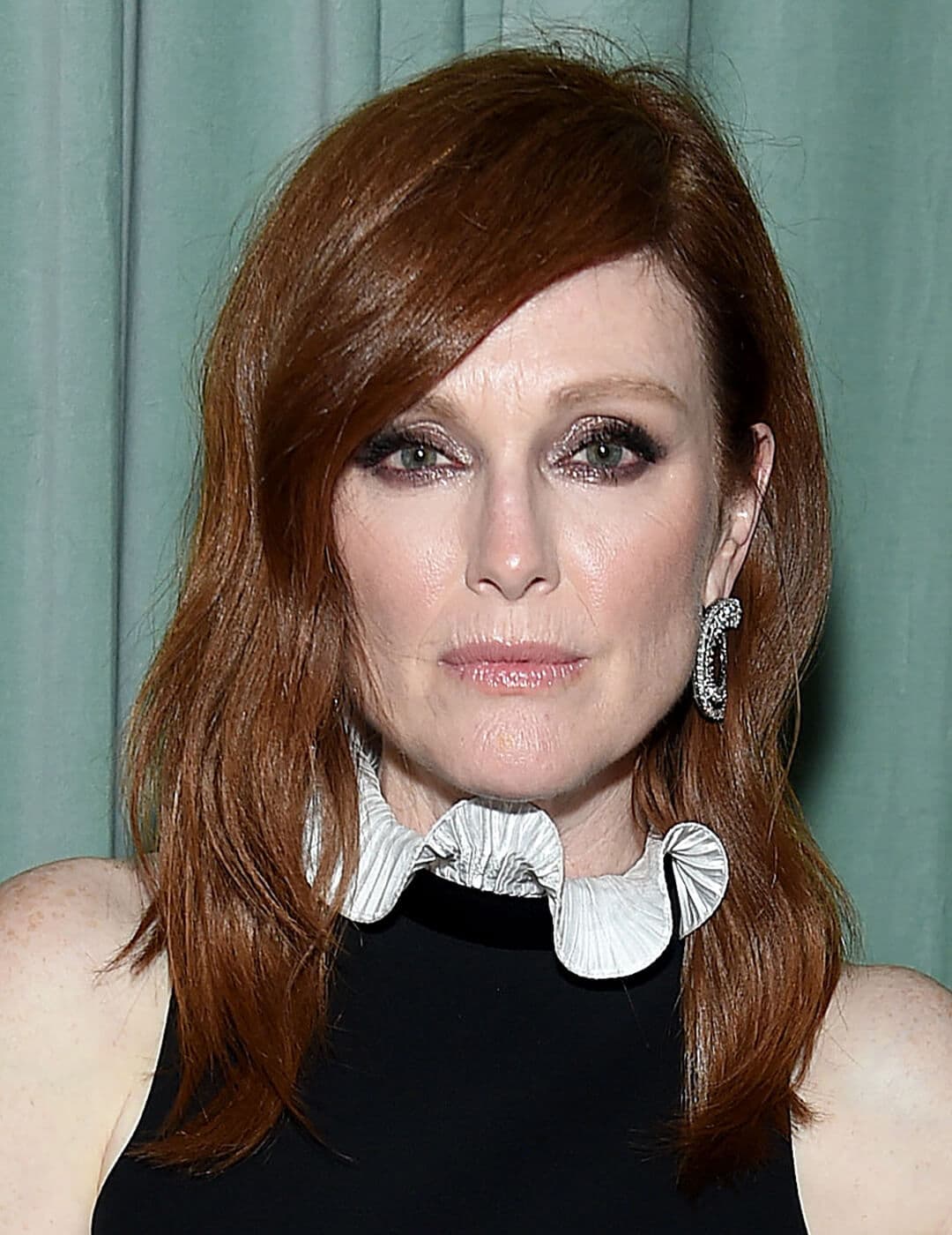 Image of Julianne Moore rocking a medium length side part hairstyle against a teal curtain