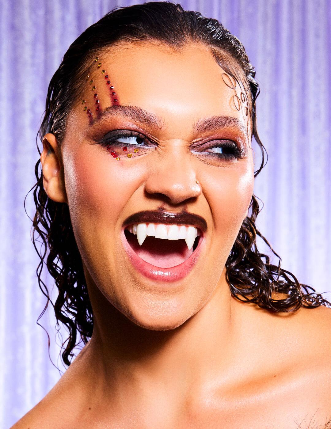 Model in a Halloween werewolf makeup look against lilac drapes background