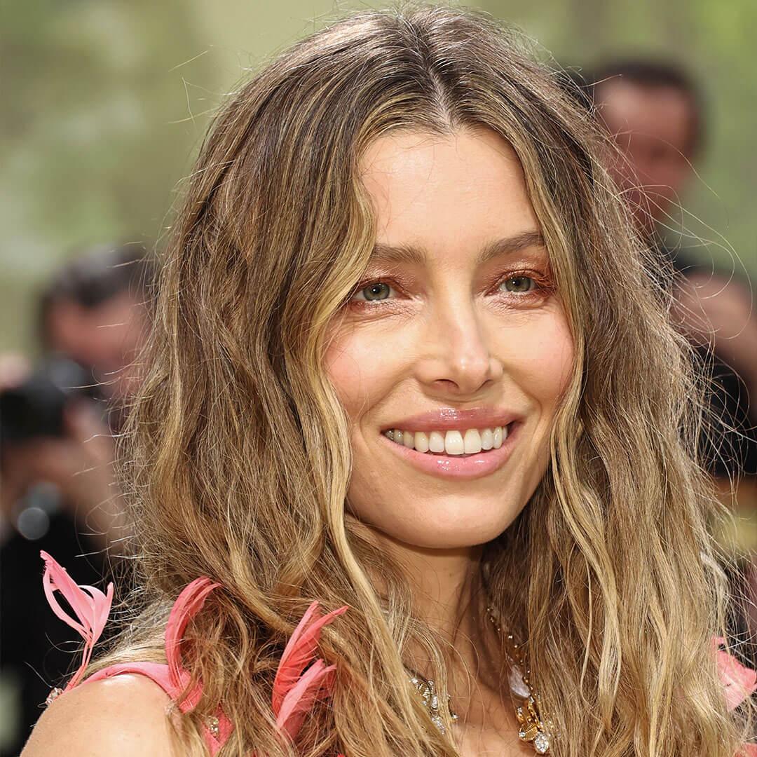 An image of Jessica Biel displaying her pink dress with her blond hair worn in a sloppy wavy way and wearing a perfectly peach monochromatic makeup