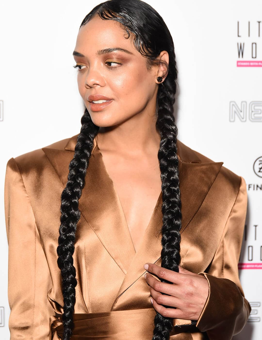 Tessa Thompson looking fierce in a braided pigtails hairstyle, bronze makeup look, and bronze suit