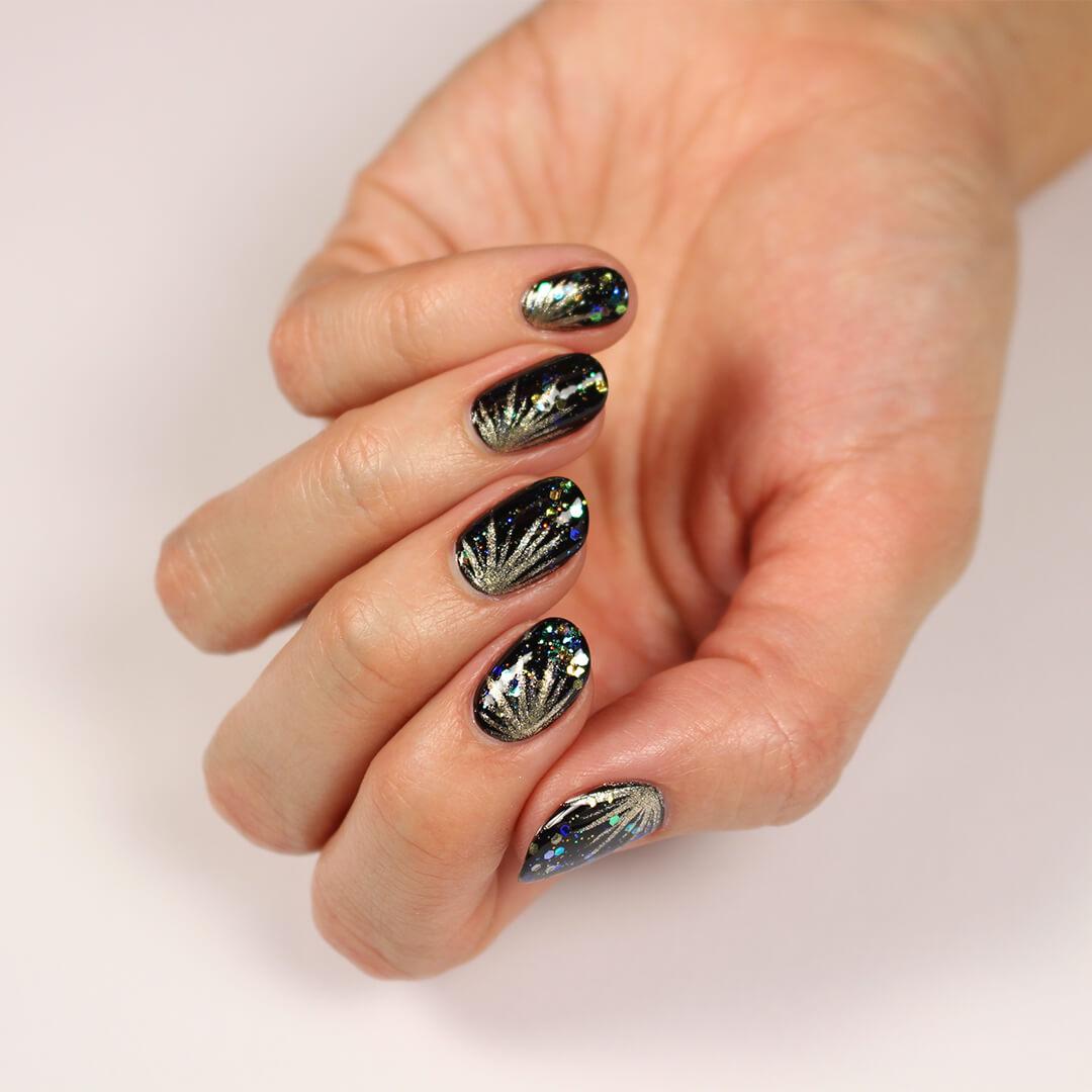 Image of a model's hand with a black, fireworks themed nail art mani