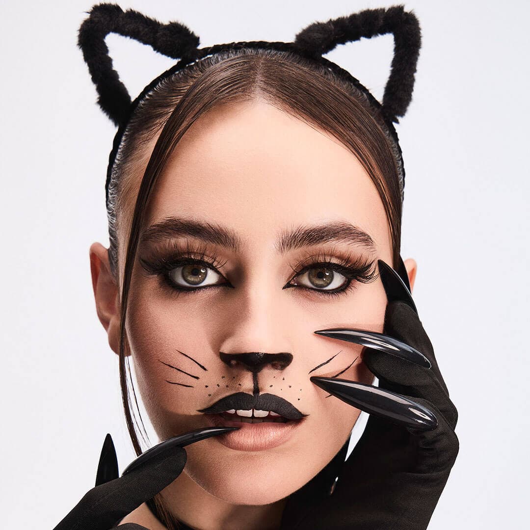 An image of a woman cosplaying as a cat woman wearing a black gloves with long black nails and a cat-ear like headband