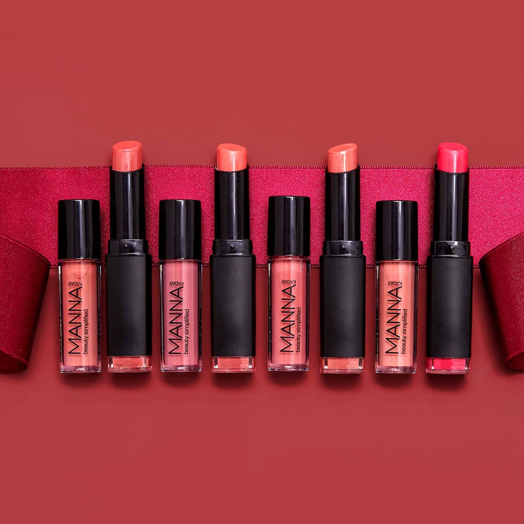 A photo of different shades of MANNA KADAR COSMETICS Lipsticks on a red background with a ribbon