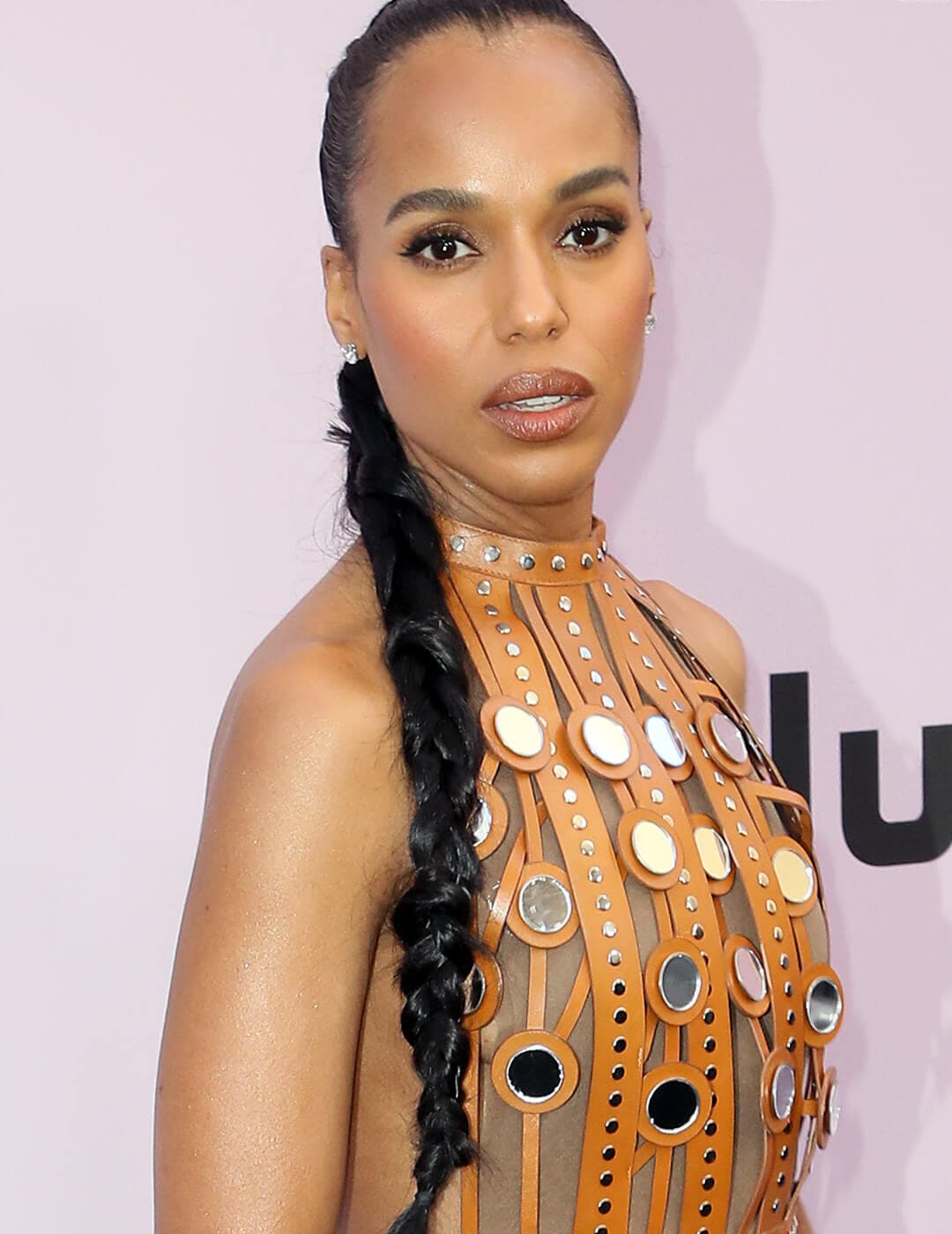 Kerry Washington rocking a braided high ponytail hairstyle and orange leather, silver studs, and mirror dress