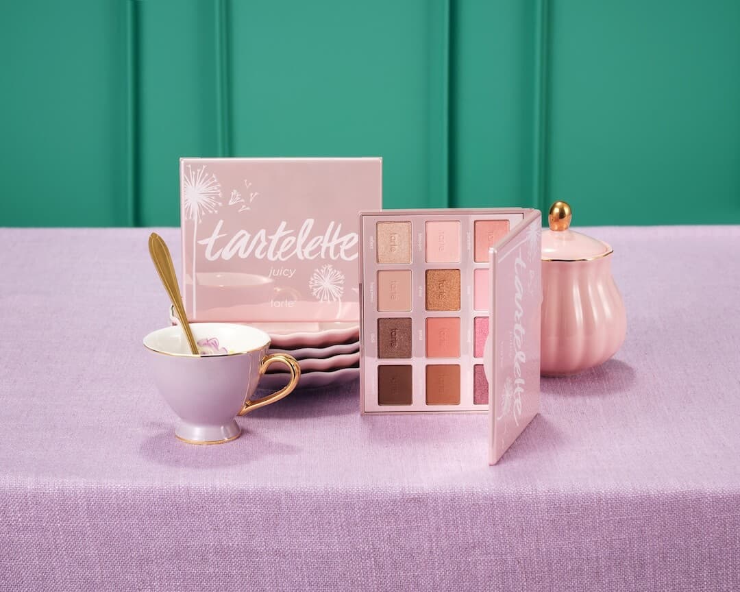 TARTE™ Tartelette™ Juicy Amazonian Clay Palette on a purple tablecloth surrounded by a tea pot and cup.