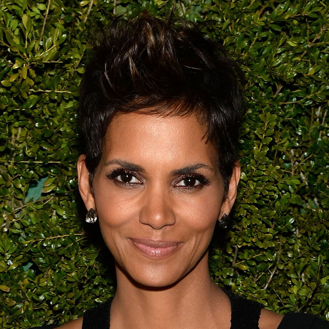 Close-up image of Halle Berry rocking a pixie cut hairstyle against a hedge background