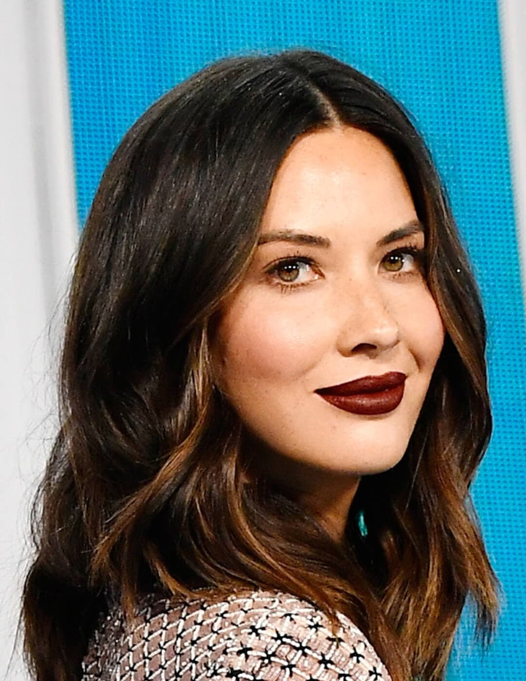 Close-up of Olivia Munn looking chic in minimal face makeup paired with dark burgundy lips