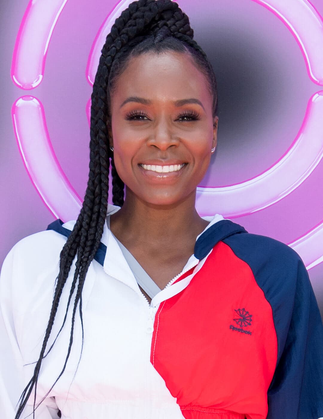 Sydelle Noel rocking a sleek braided updo hairstyle and red, blue, and white jacket