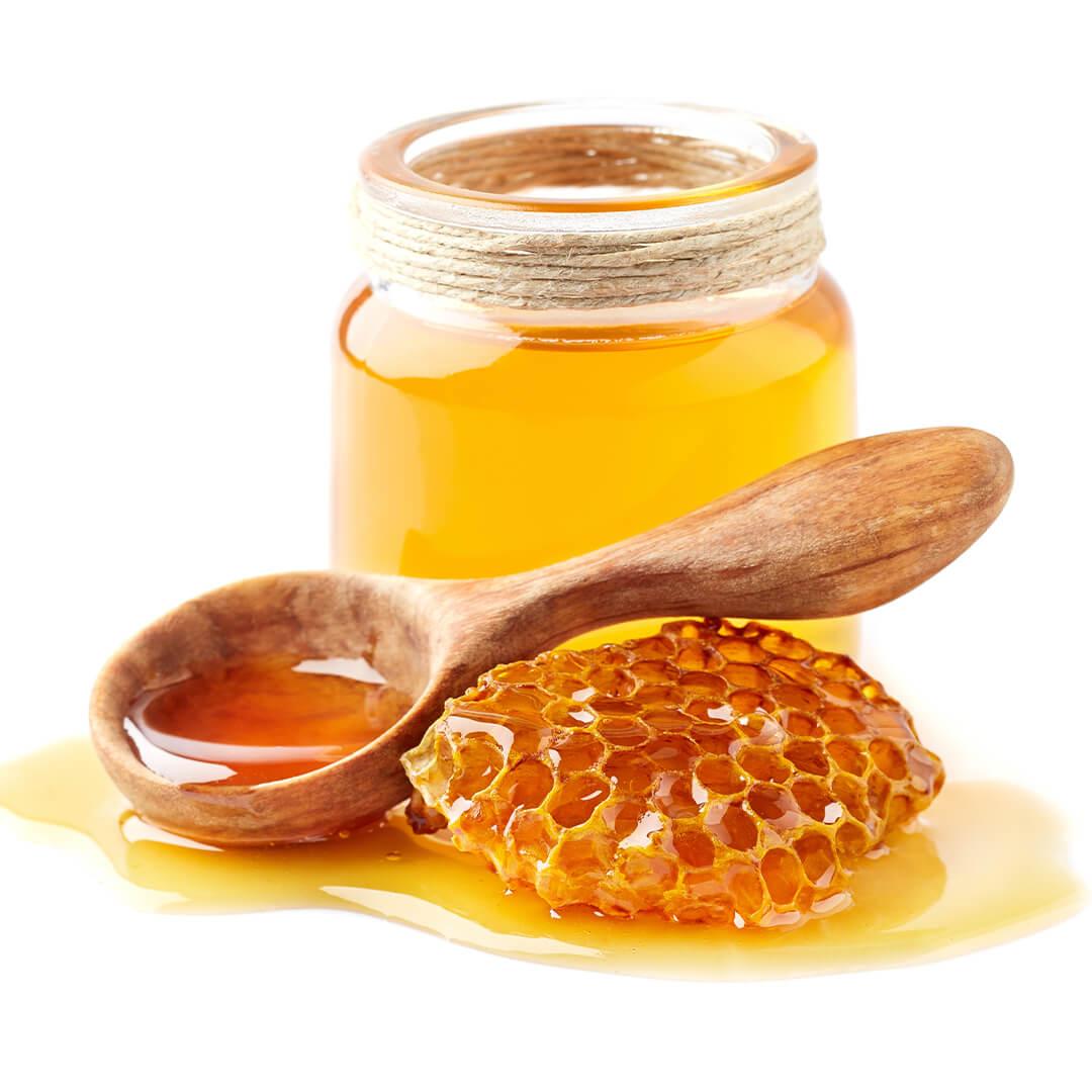 Image of a jar of honey, honeycomb, and wooden spoon on white background