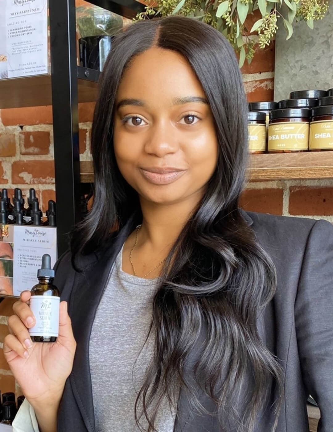 MARY LOUISE COSMETICS founder Akilah Mary-Louise Releford posing and holding a bottle of skincare product