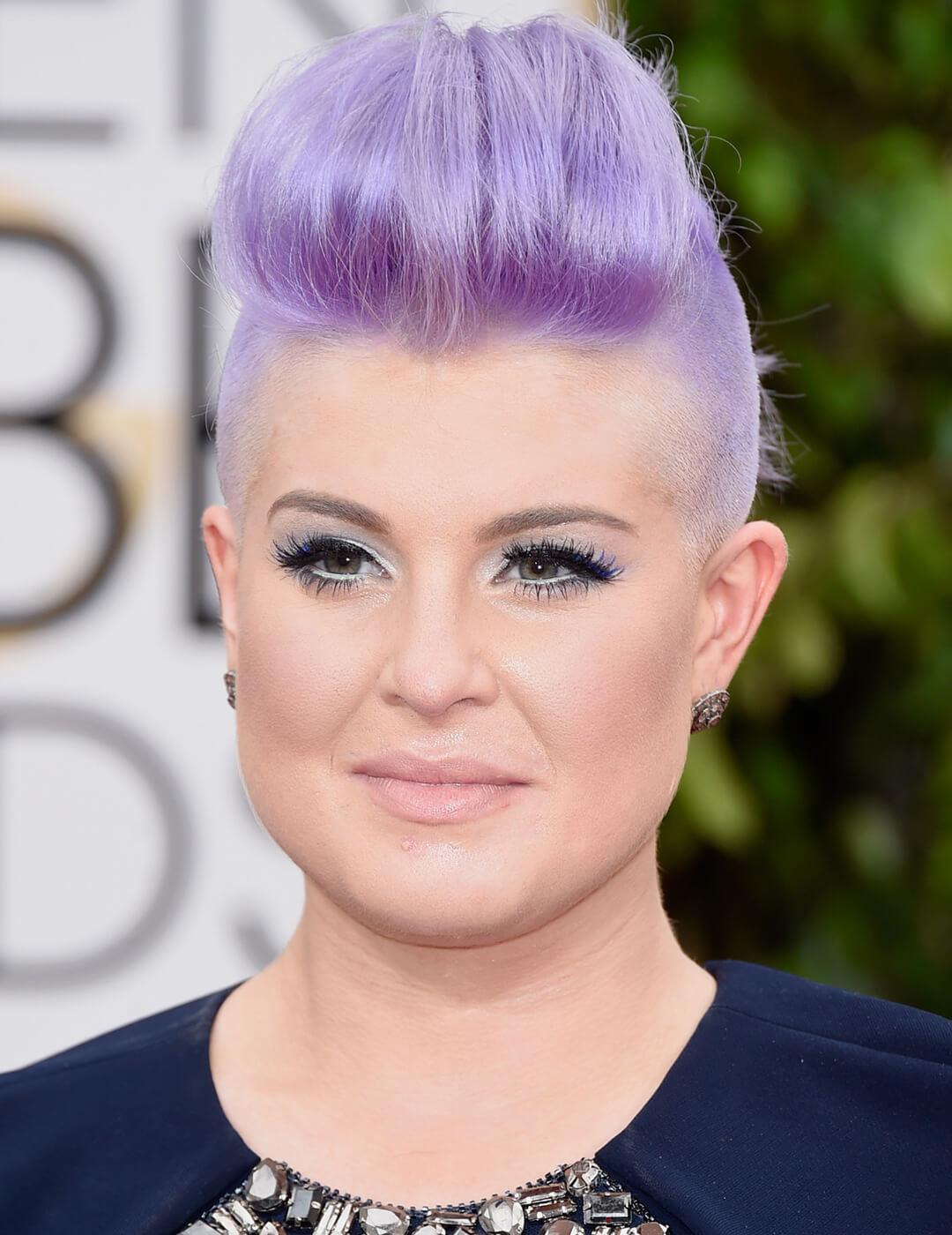 Kelly Osbourne rocking a lavender-colored undercut updo hairstyle, lavender eyeshadow makeup look, and nude lips