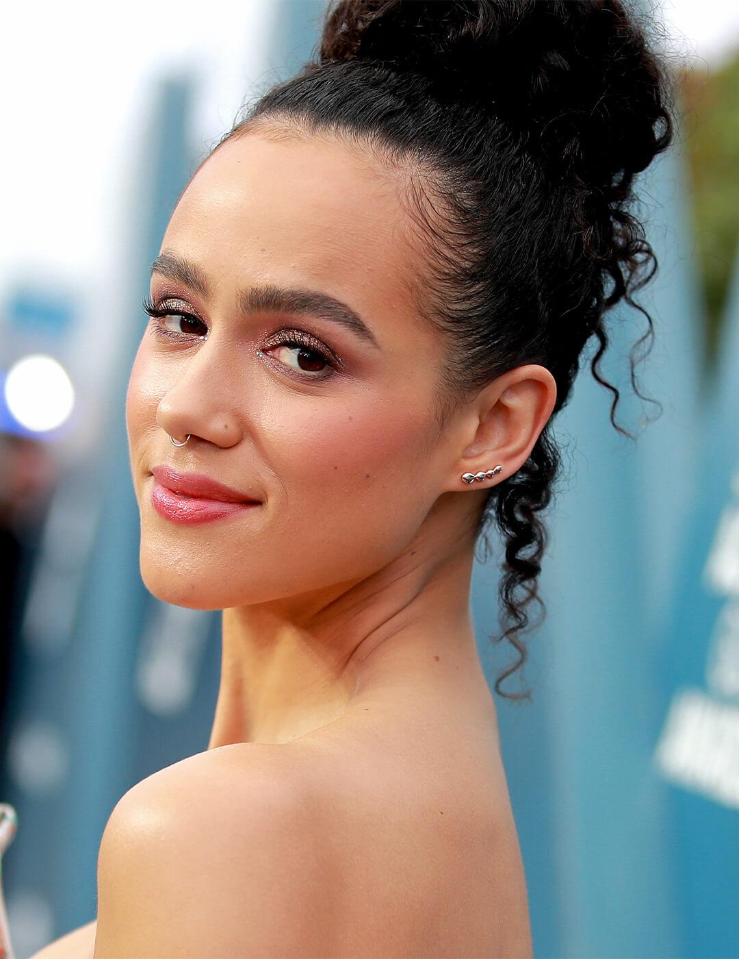 Nathalie Emmanuel wearing a loose top knot hairstyle smiling