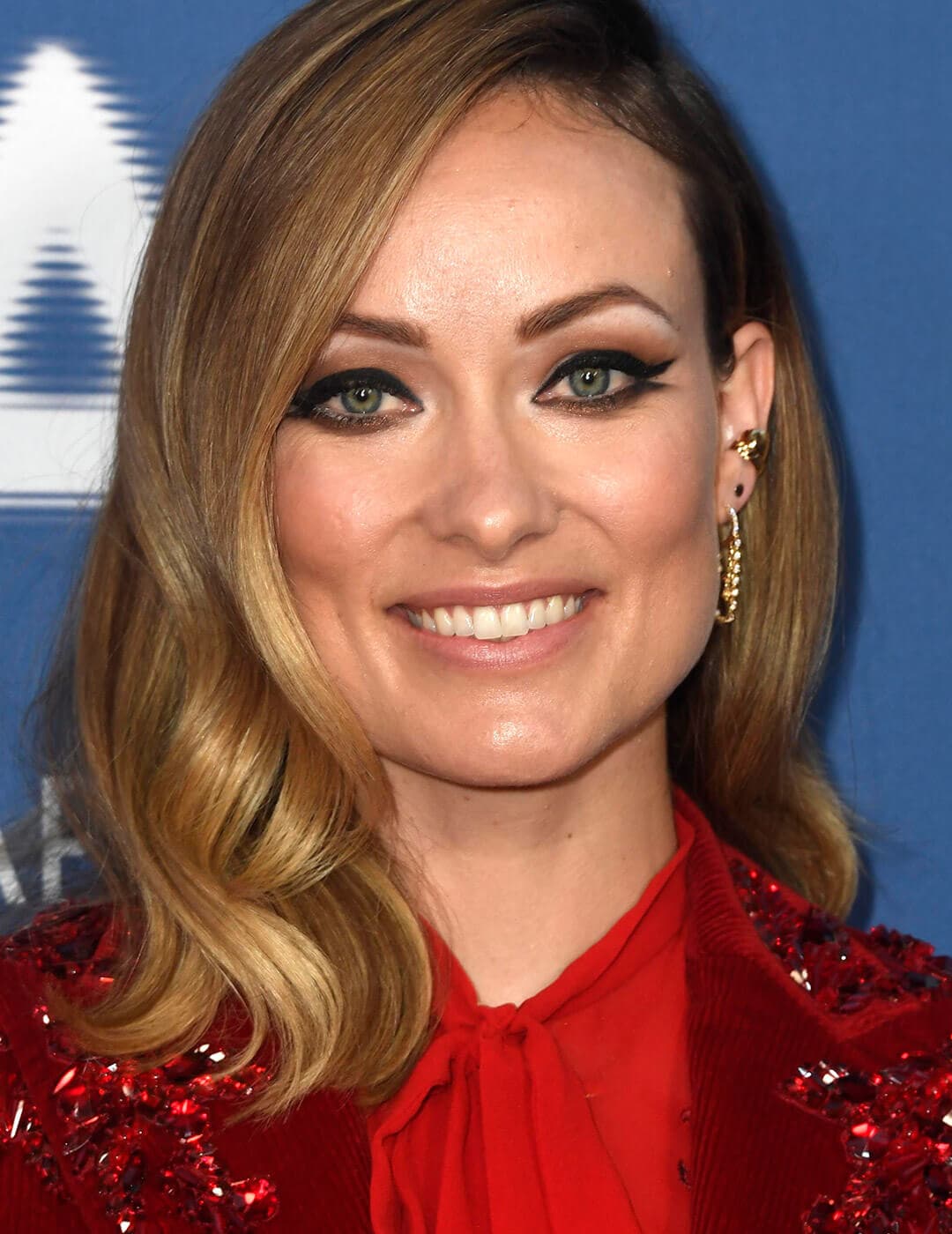 Smiling Olivia Wilde rocking a red sequined dress and smudged double wing eyeliner look