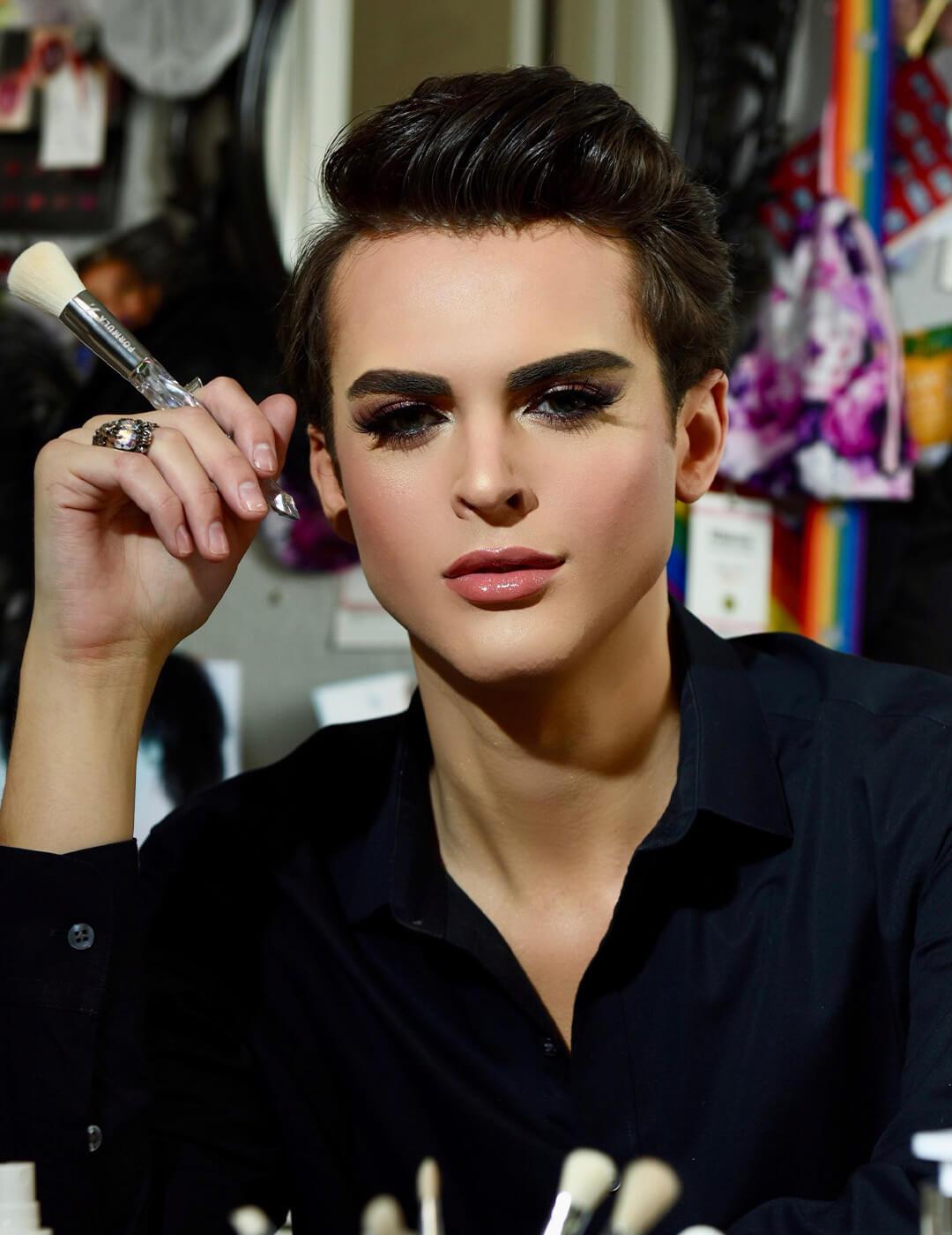 Portrait of Zach Dishinger holding a makeup brush