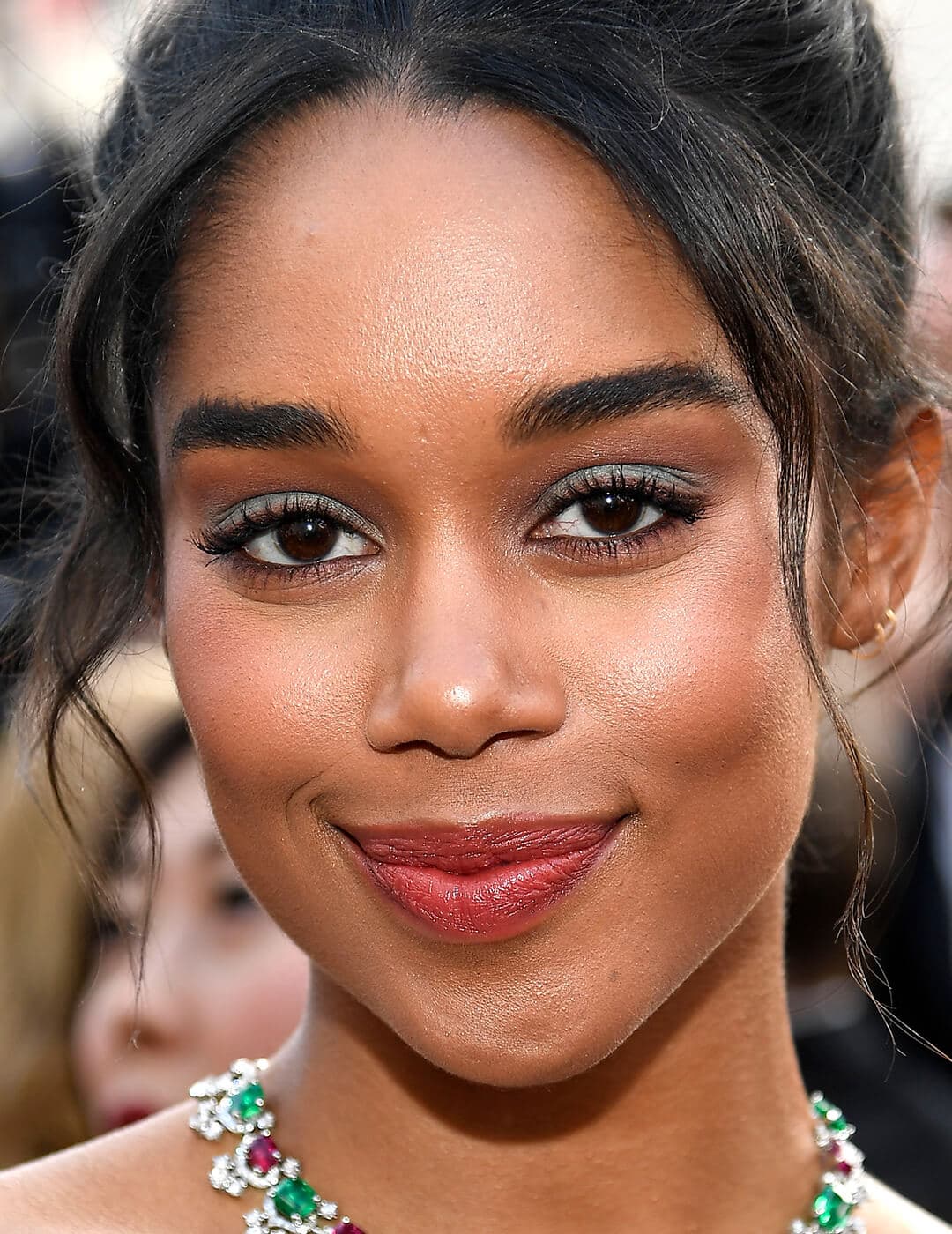 A photo of Laura Harrier with grey eyeshadow and a pinky-nude lip color