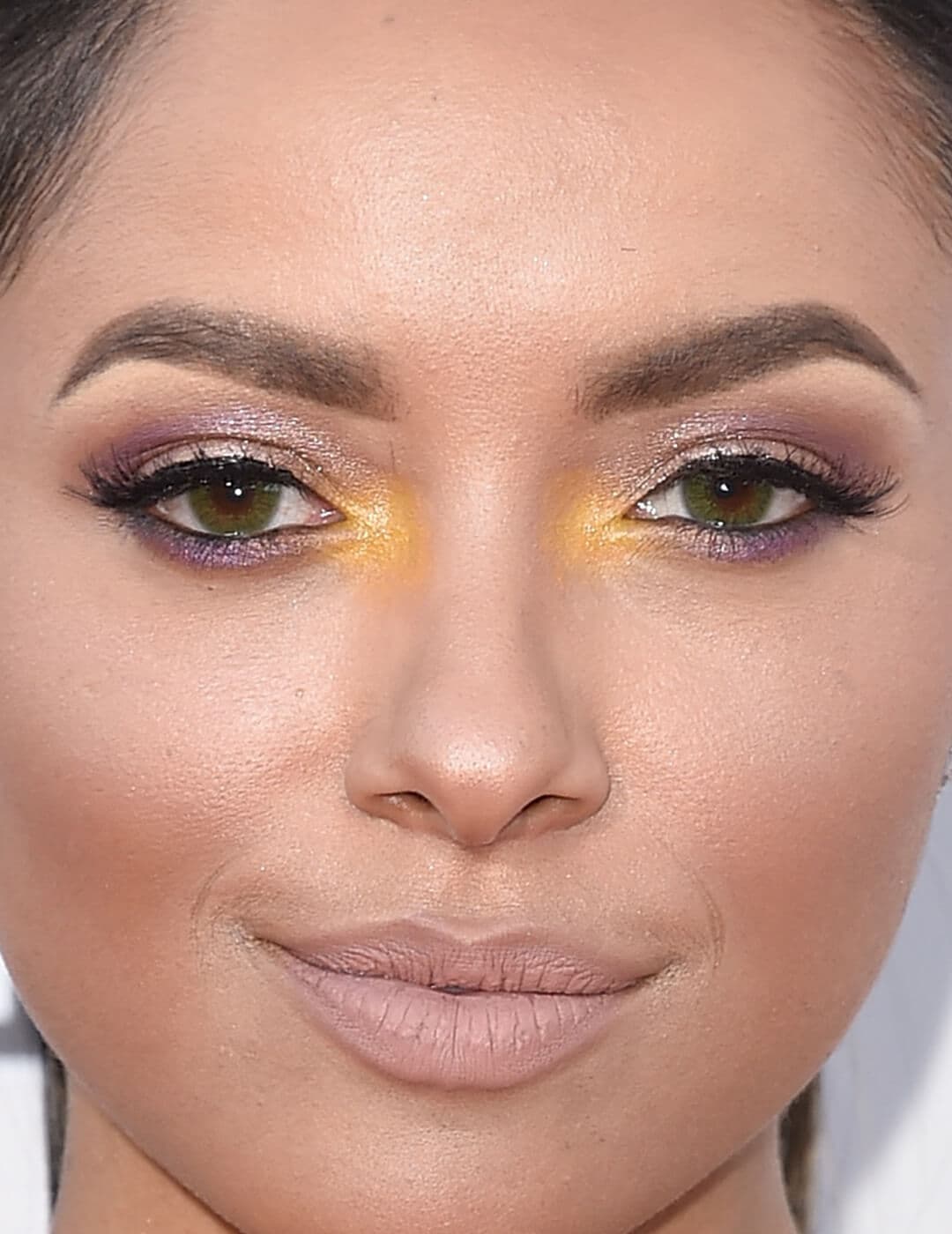 Close-up image of Kat Graham rocking a purple and yellow eye makeup look paired with a nude lip