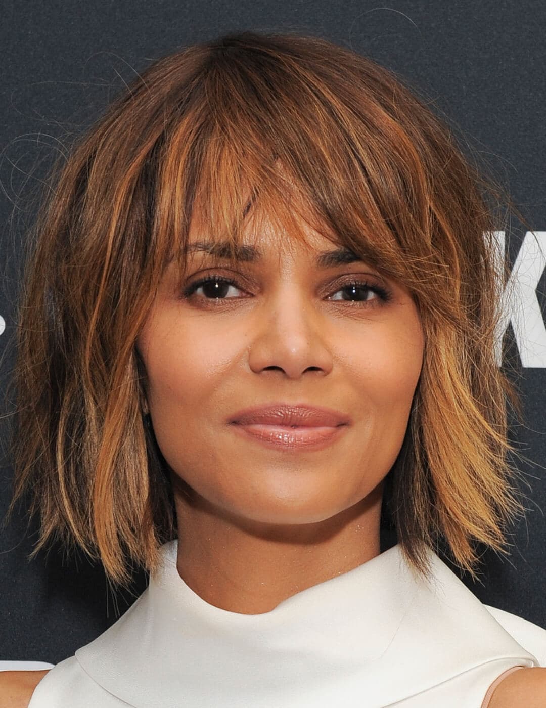 A photo of Halle Berry with a voluminous shag wearing a white sleeveless turtleneck top