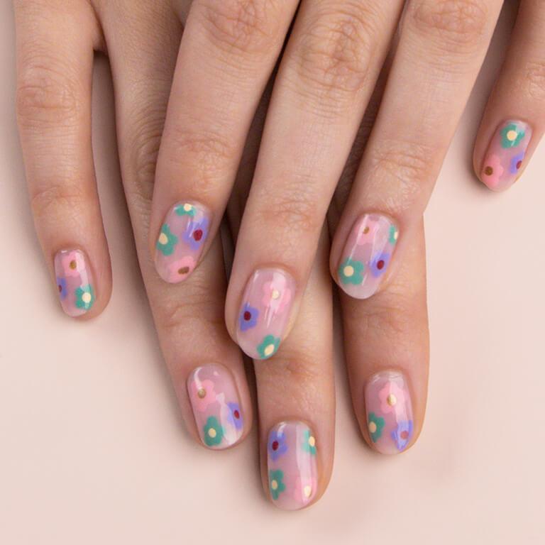 A close-up image of a model's hands with pastel colored flowers nail art