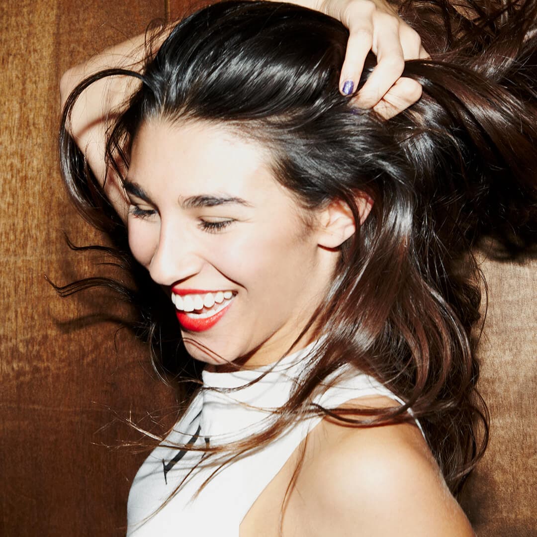 A photo of a model smiling while holding her hair