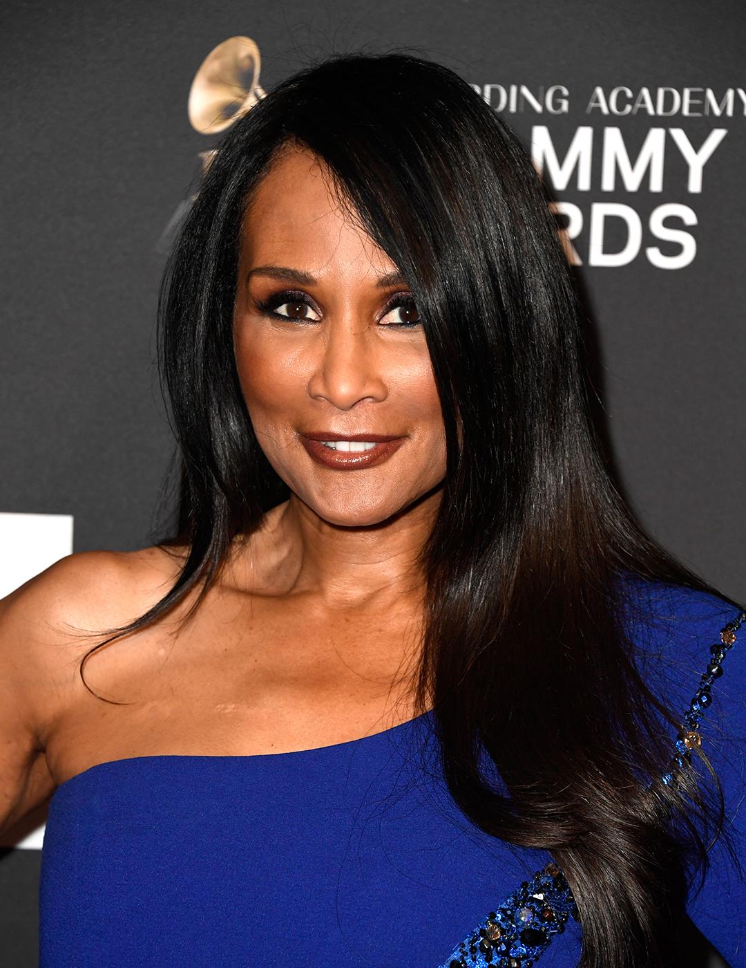 A photo of Beverly Johnson in her black layer of her sleek long hair clad in a blue one shoulder top dress 