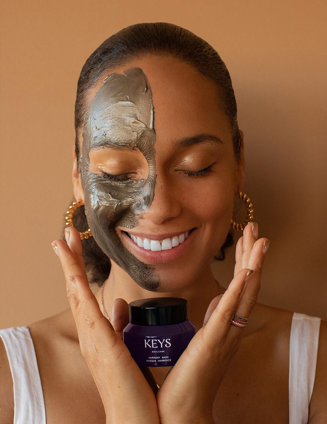 KEYS SOULCARE Founder Alicia Keys with mud mask on her face while holding KEYS SOULCARE Harmony Mask