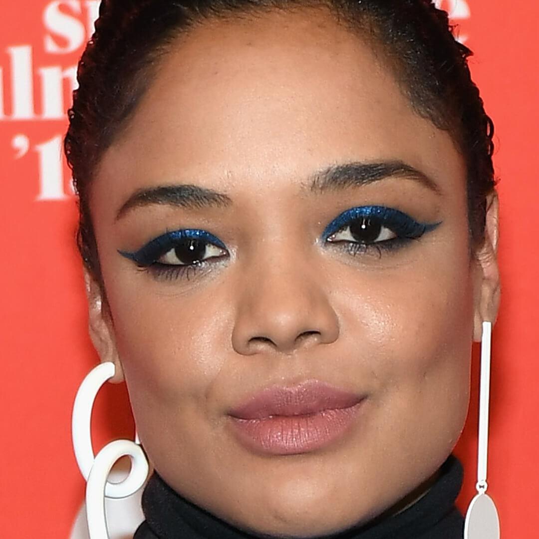 Close-up image of Tessa Thompson rocking a glittery blue eyeshadow look paired with nude lipstick