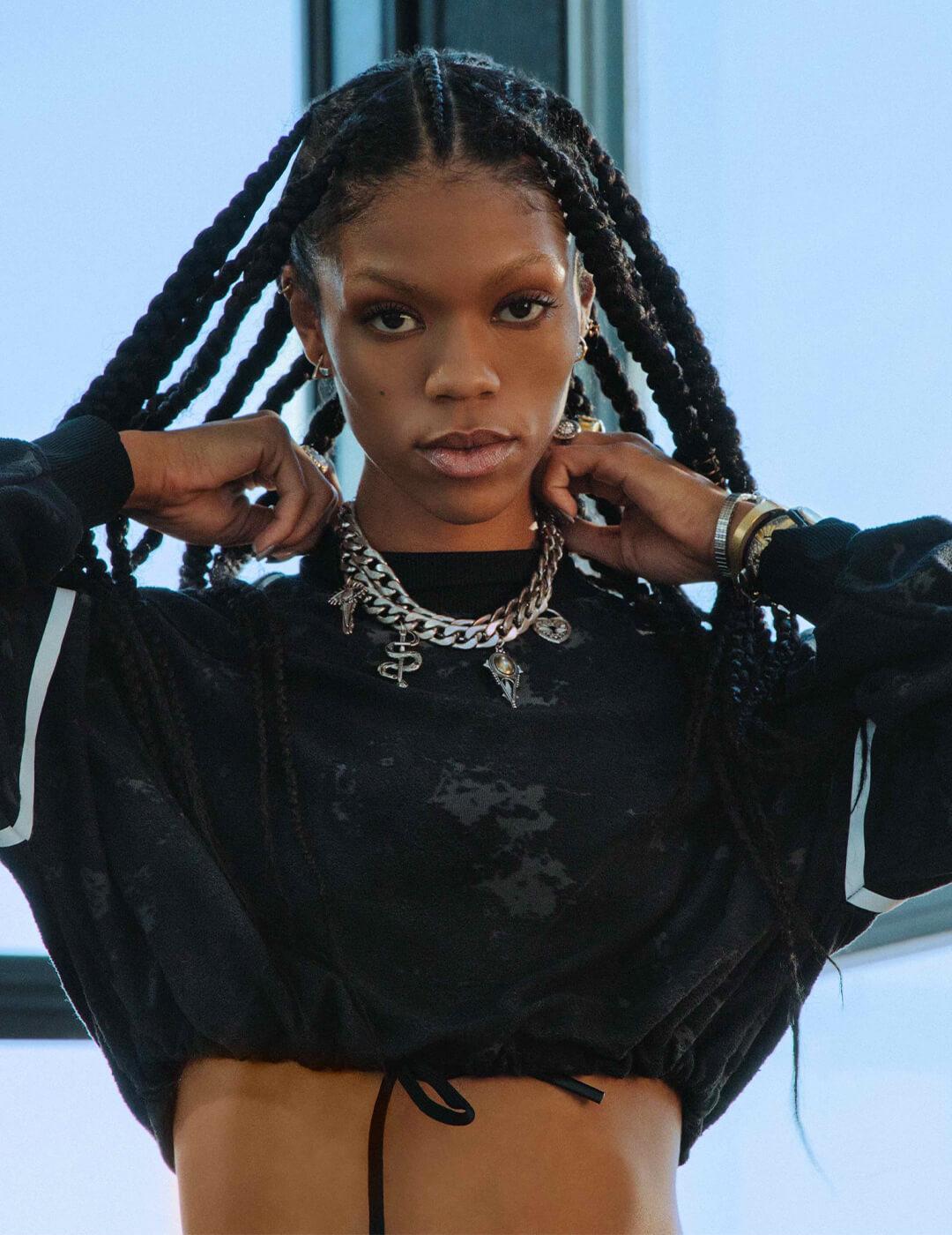 Vashti Cunningham looking fierce in a black cropped top, long box braids, and a silver necklace