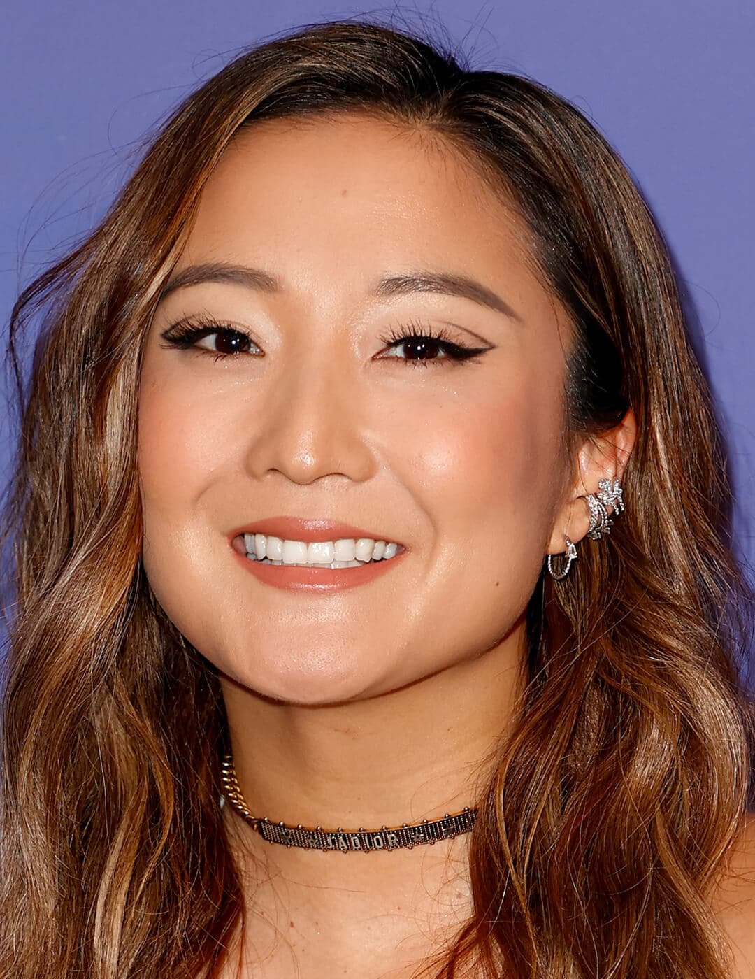 Smiling Ashley Park rocking a graphic eyeliner makeup look on the red carpet