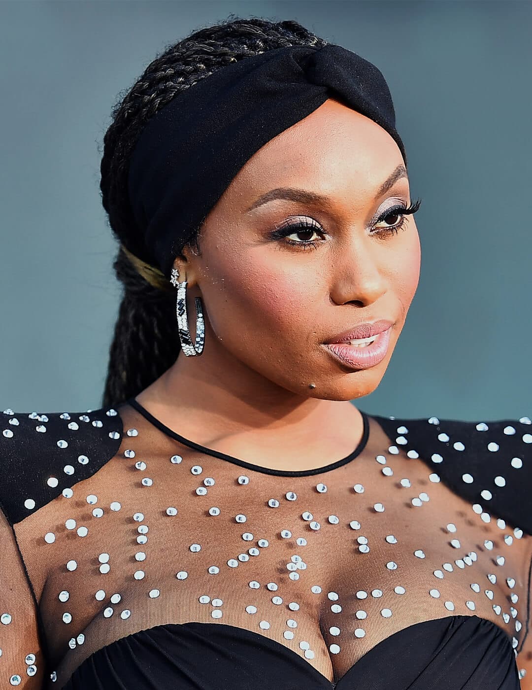 Angell Conwell looking glamorous in a black dress with silver sequin accents and rocking a braided hairstyle with headband