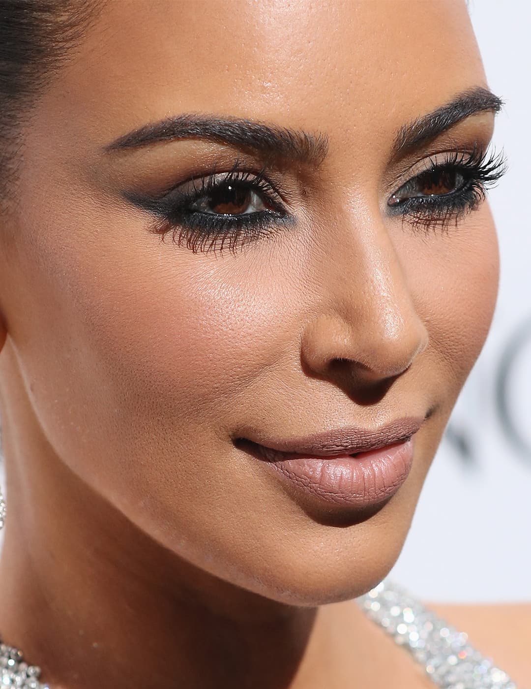 A photo of Kim Kardashian wearing a diamond earring, nude lipstick and a black eyeliner