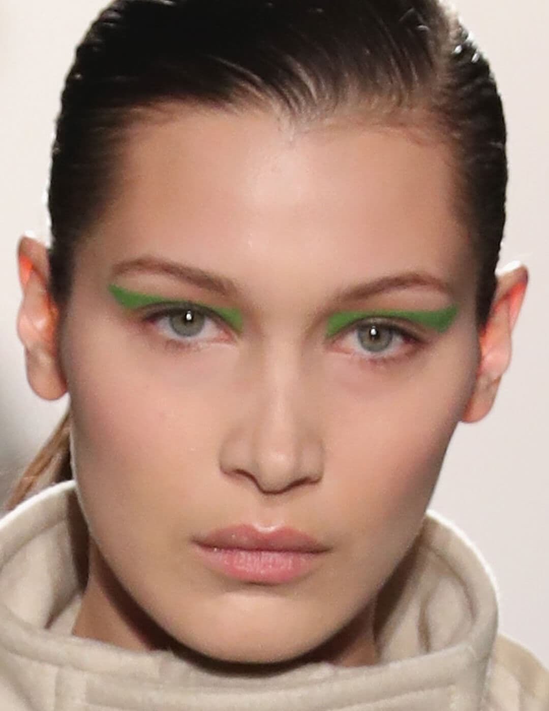 Close-up of Bella Hadid with a bold, neon green eyeliner makeup look
