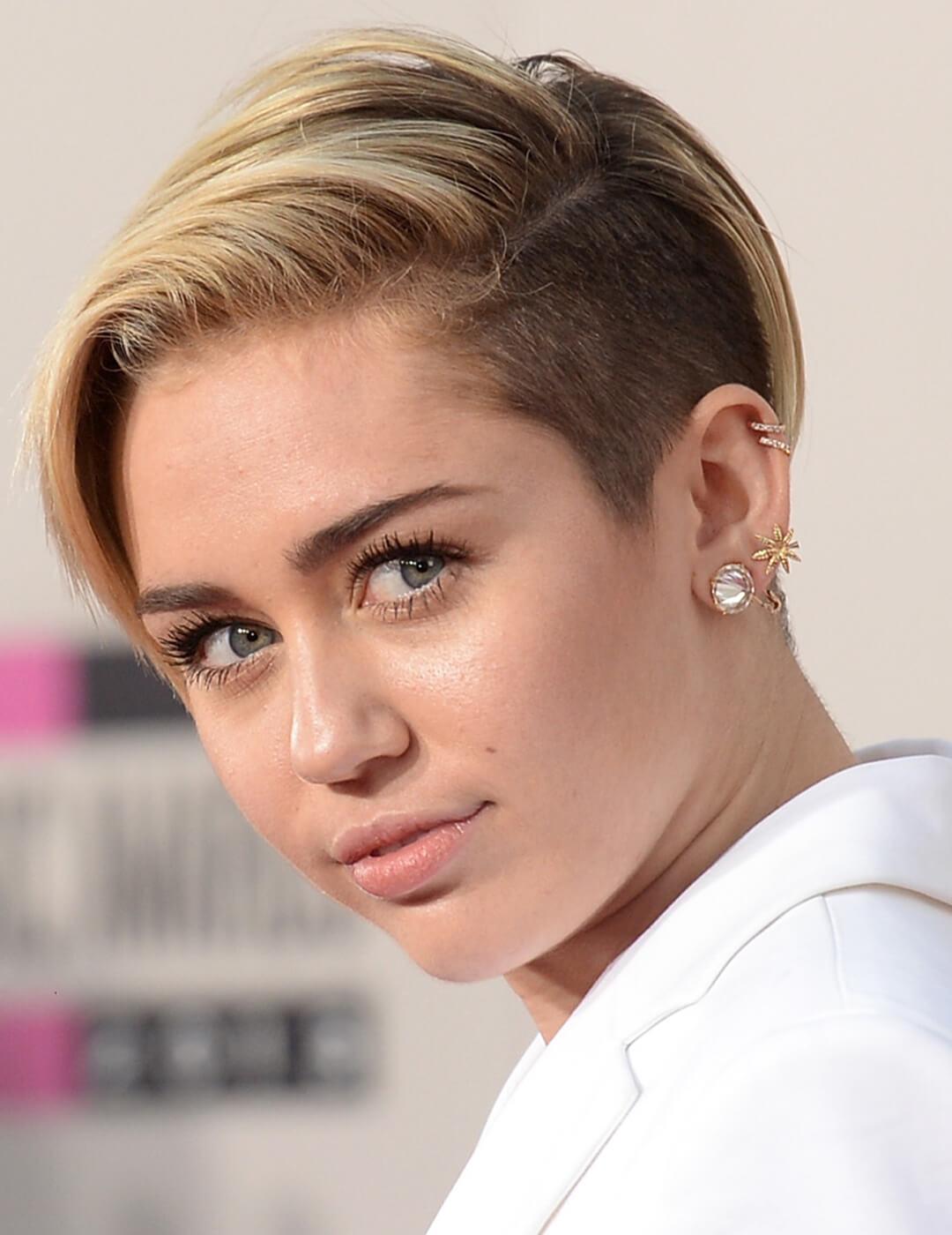 Close-up of Miley Cyrus rocking a long pixie undercut hairstyle and white suit