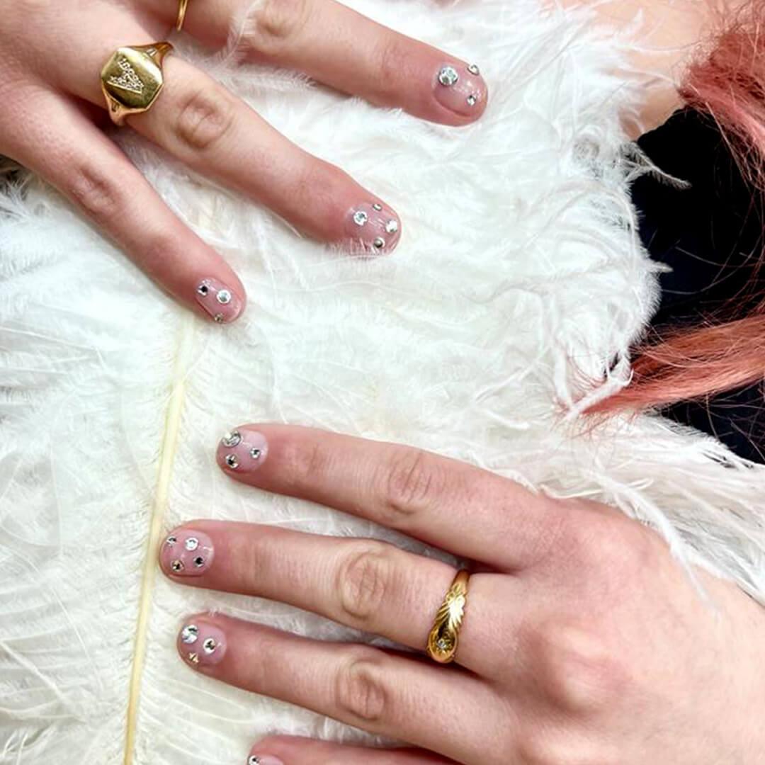 A closeup of hands on fur with dazzling gems nail art