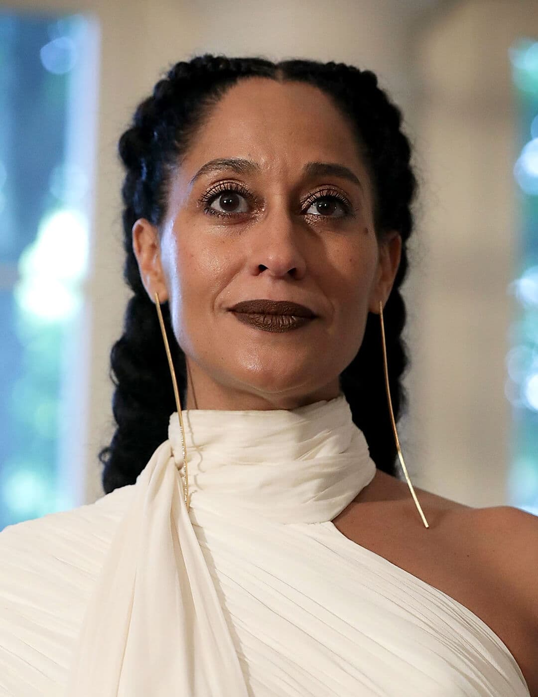 Tracee Ellis Ross looking elegant in a white, venus-cut dress, long dangling earrings, and French braids hairstyle