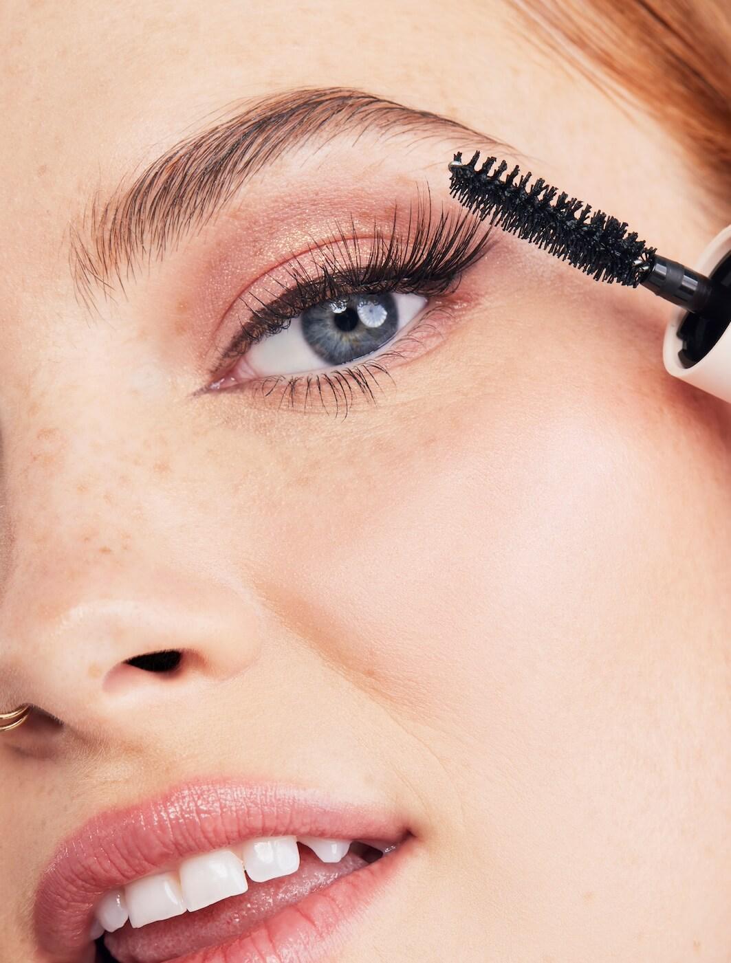 Close-up image of a woman putting on mascara