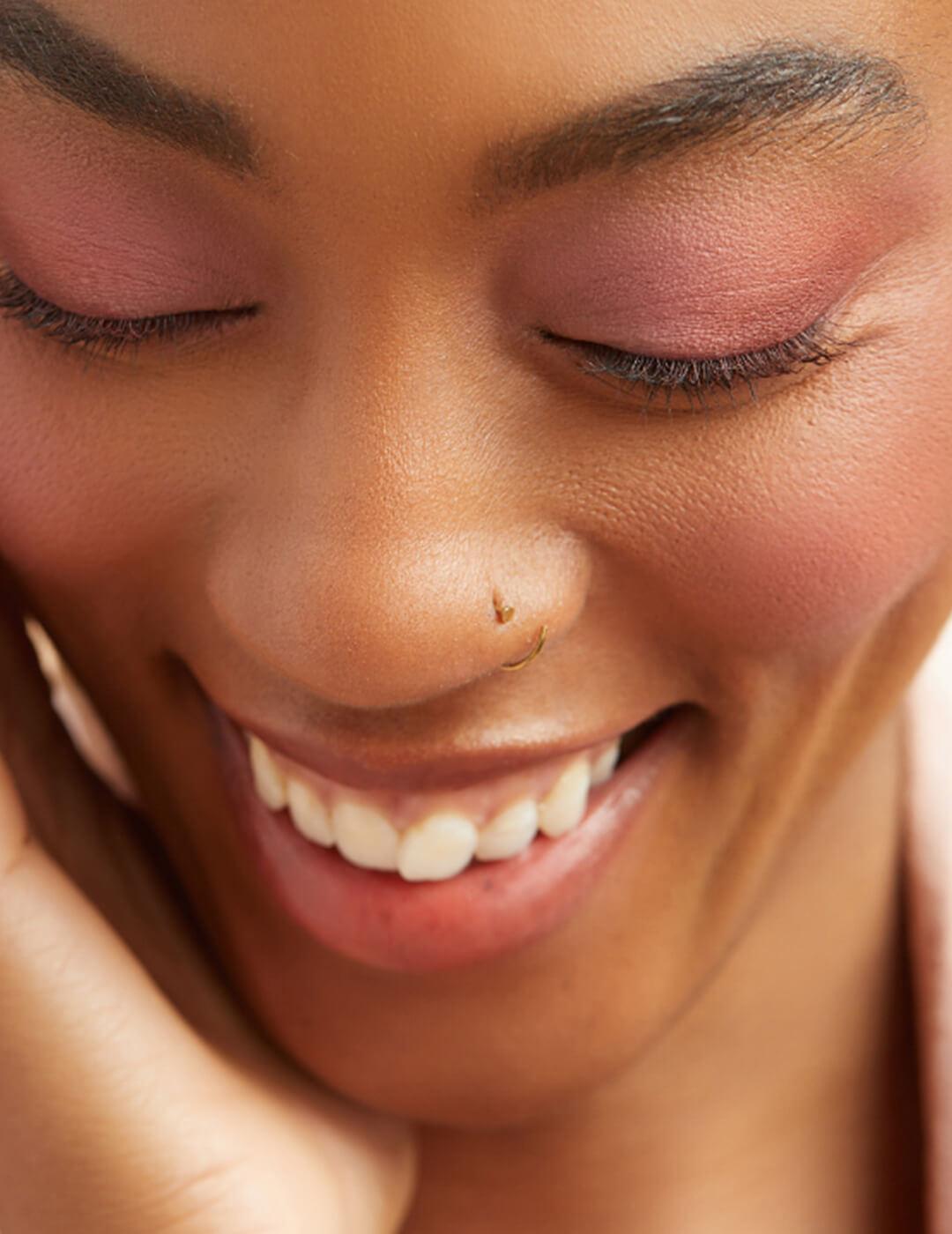 Close-up of a smiling model rocking a rose eyeshadow and blush makeup look