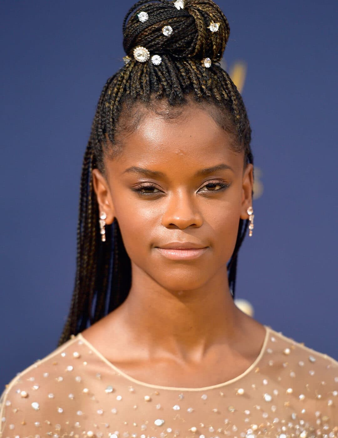 A photo of Letitia Wright with a braided bun and a hair accessories