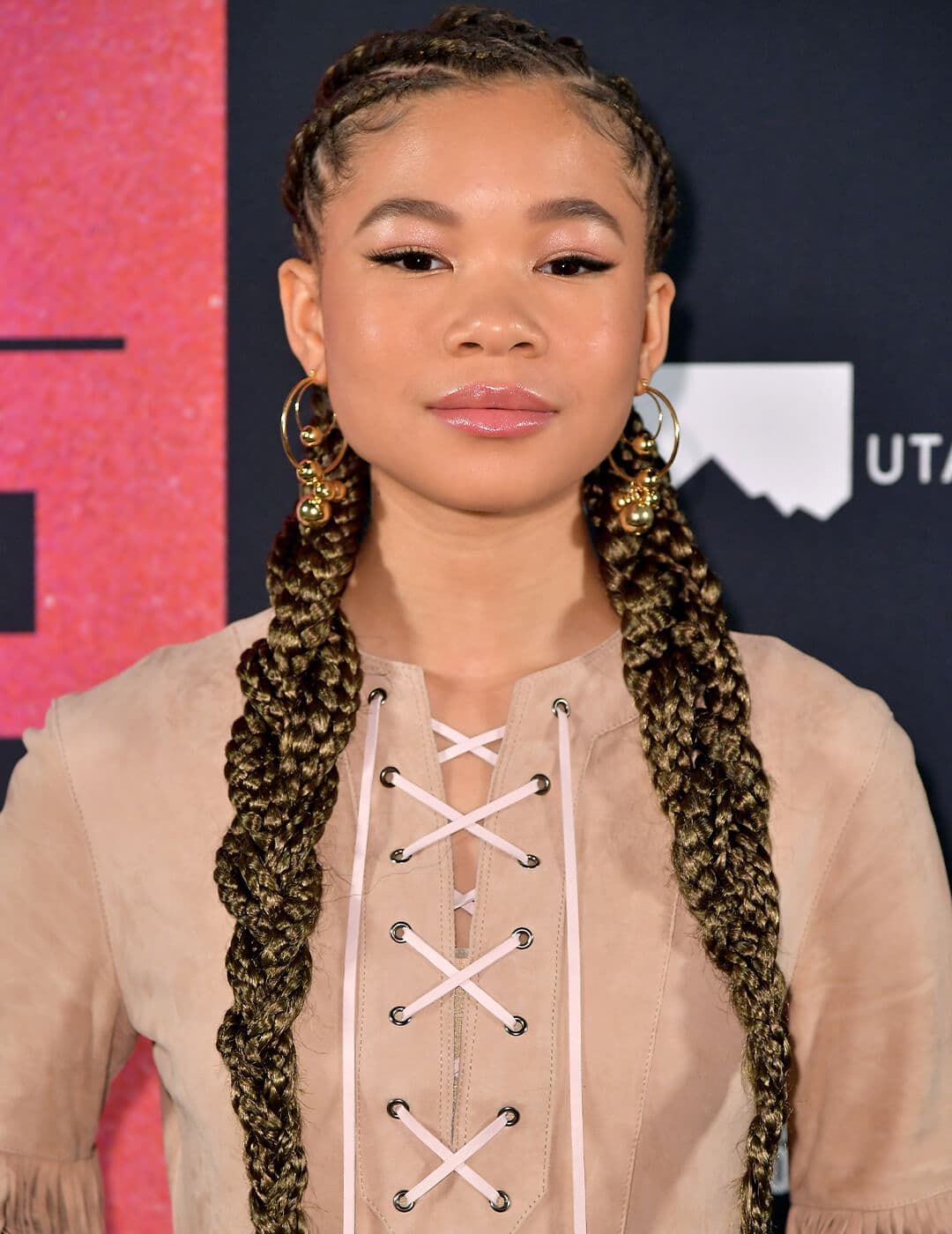 Storm Reid wearing a brown outfit and rocking a braided pigtails hairstyle
