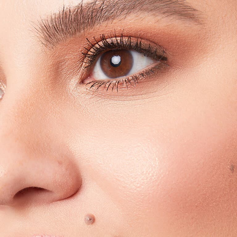 A closeup image of a model wearing copper eyeshadow and subtle blush