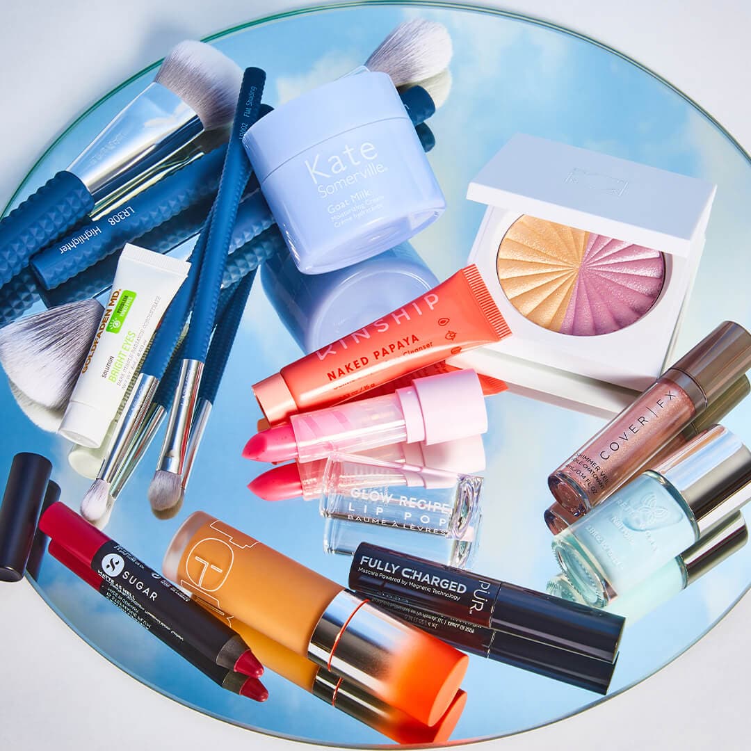 Image of nail, skincare, and makeup products and tools on round mirror with reflection of the sky