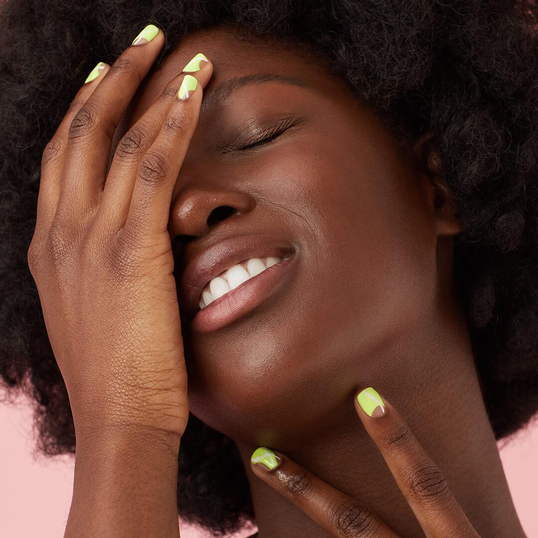 Close-up of a Black model with clear skin posing with her hands with slime green abstract nail art