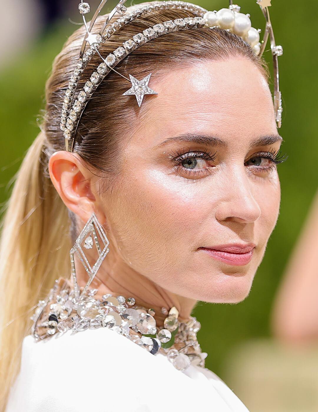 Emily Blunt rocking a glowy makeup look and silver and pearls jewelry at the red carpet
