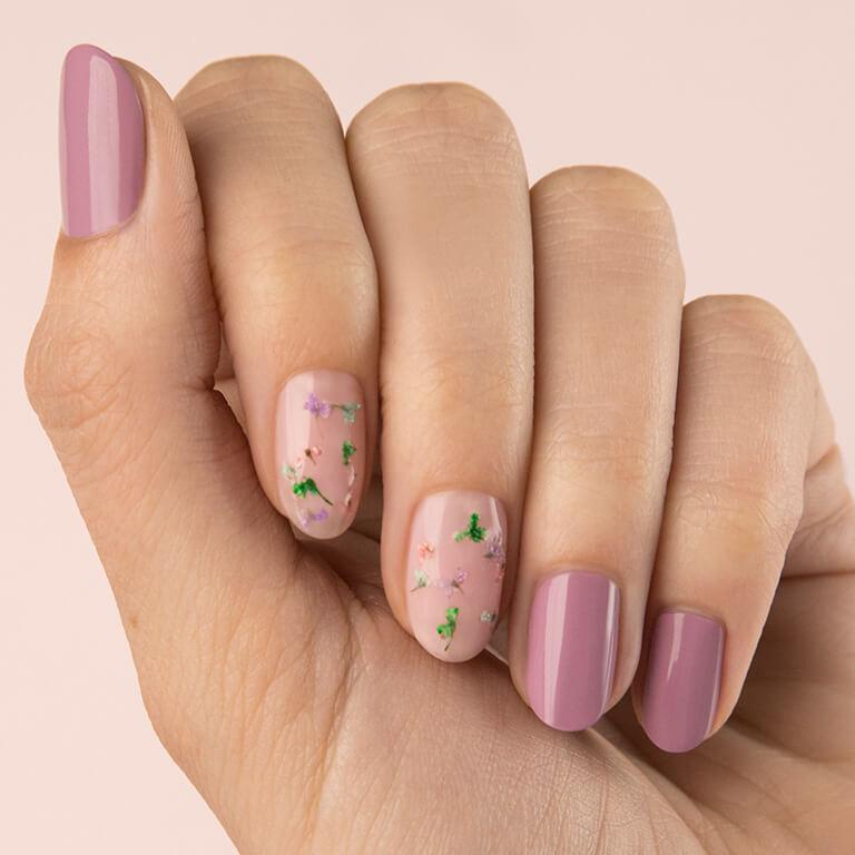 Close-up image of a model's hand with dried flowers nail art