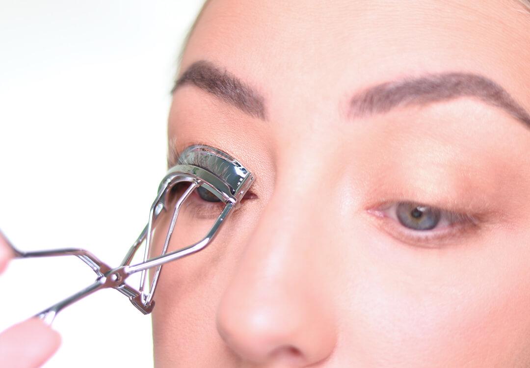 Close-up image of Anne Baker curling her lashes