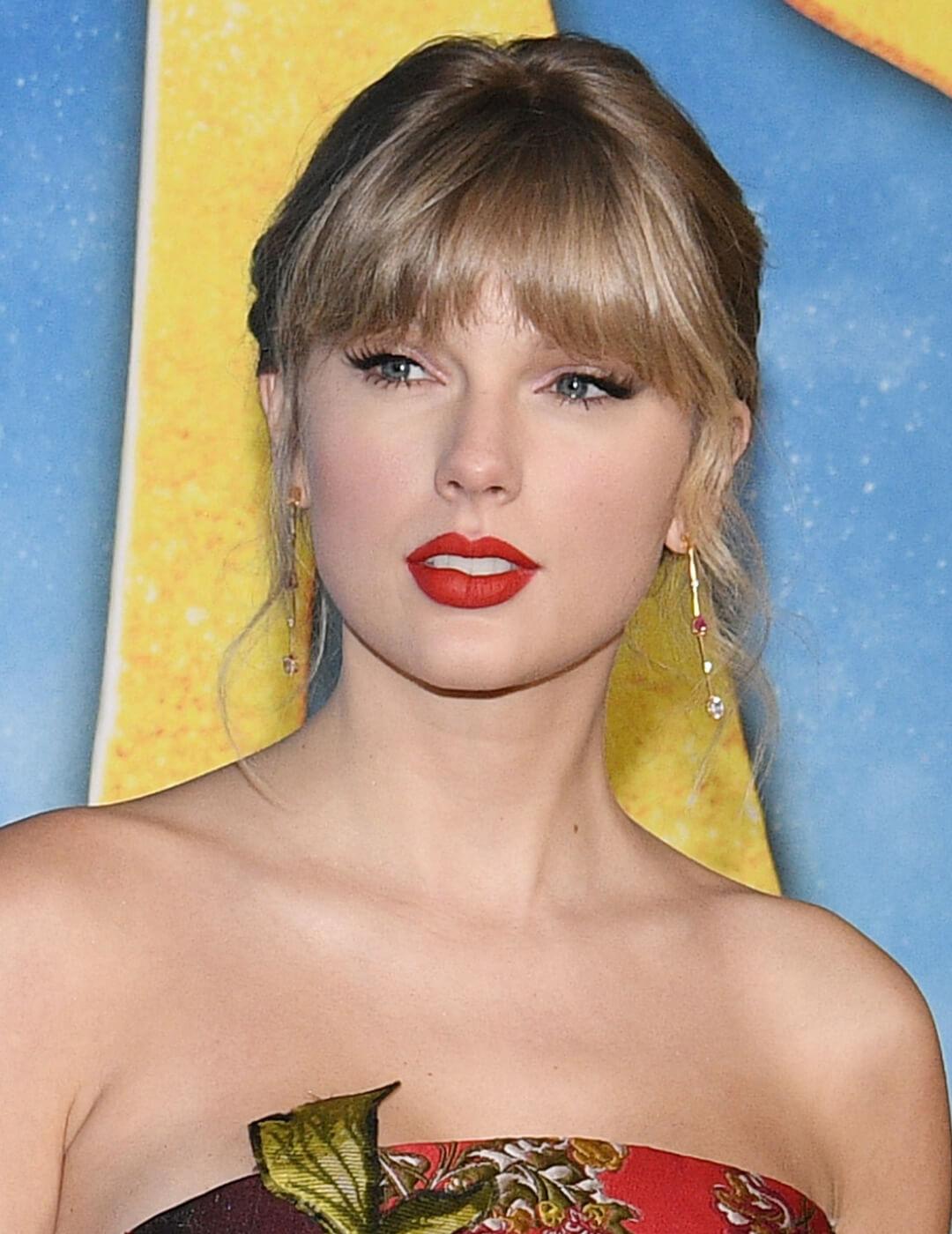 Taylor Swift rocking the red carpet in a floral dress and neutral makeup with red lips