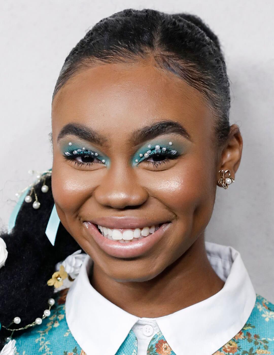 Close-up of a smiling Jordan Rice rocking blue eyeshadow makeup embellished with pearls