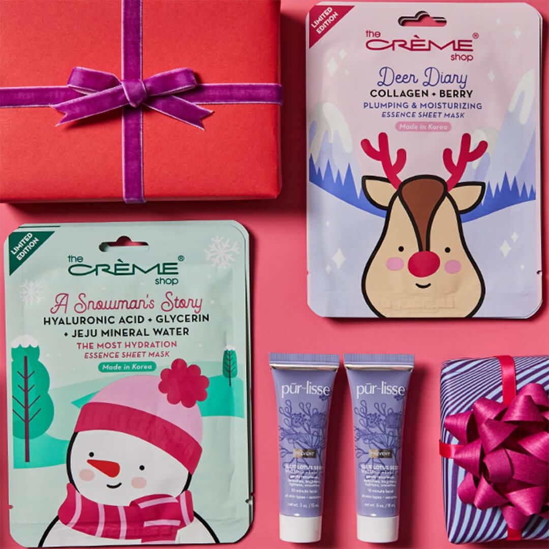 Flat lay image of THE CRÈME SHOP Holiday Sheet Mask Duo - A Snowman's Story + Deer Diary, two tubes of PURLISSE BEAUTY BLUE LOTUS Seed Mud Mask + Exfoliant, and colorful gift boxes on pink background