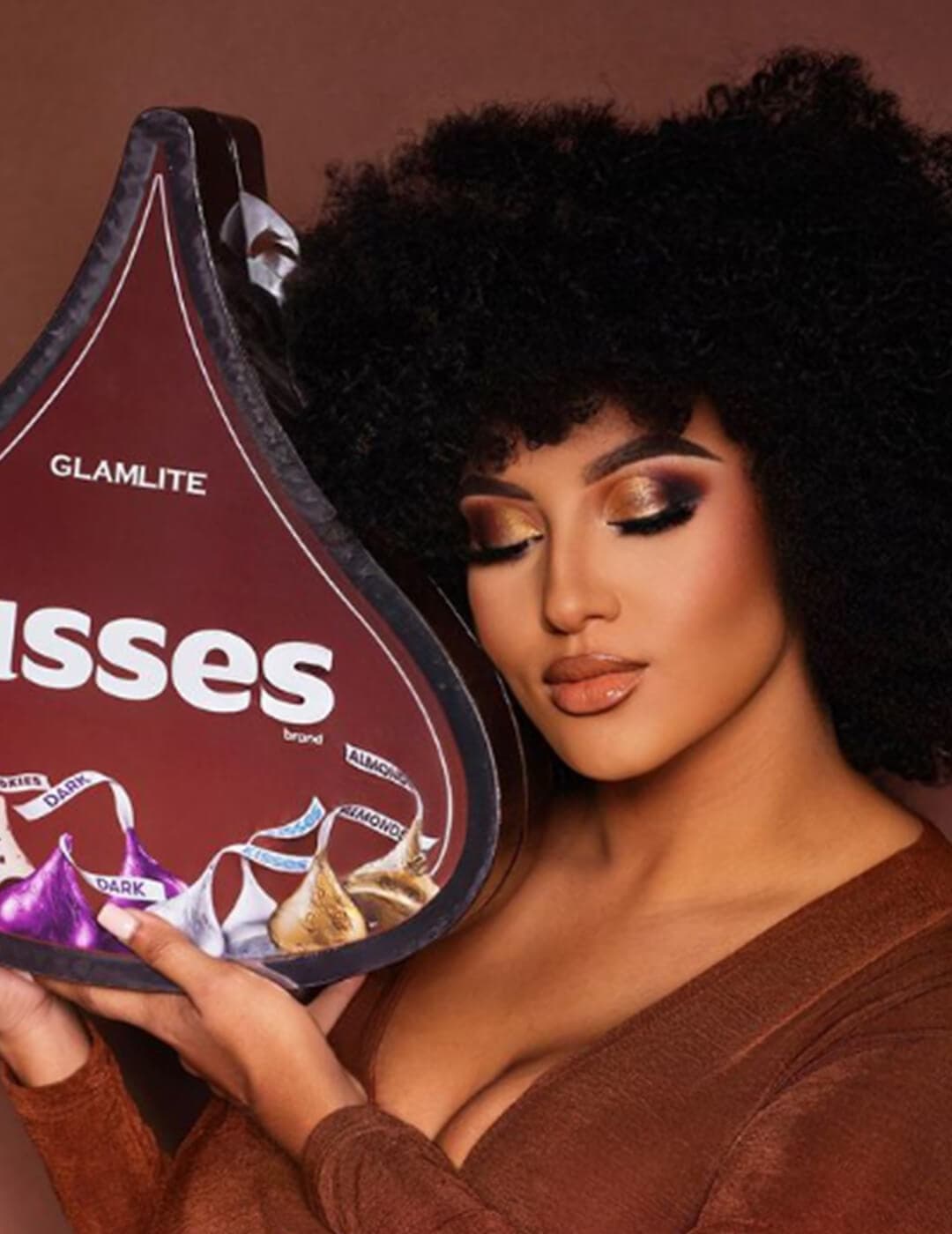 Close-up of a glam Giselle Hernandez holding the Hershey's KISSES x GLAMLITE limited edition bundle