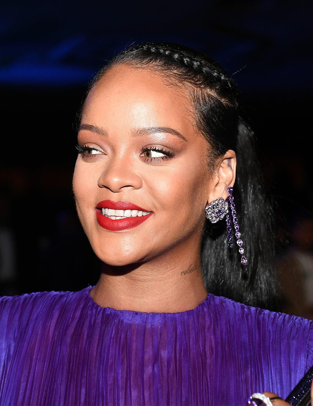 Rihanna looking glam in a purple dress and braided hairstyle