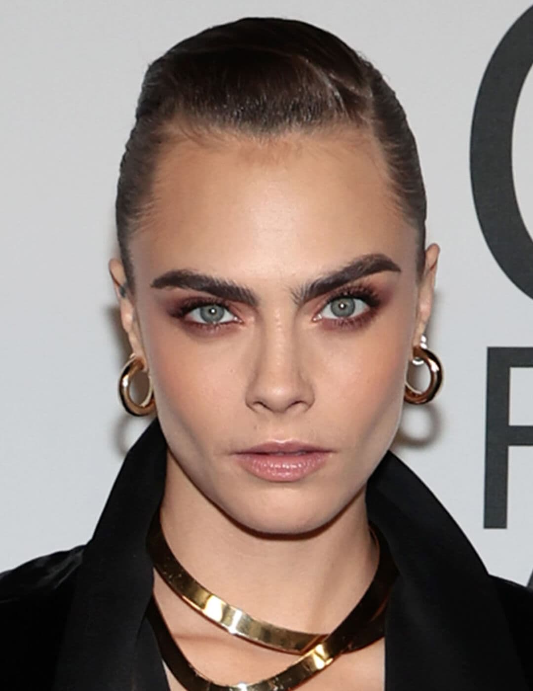 A picture of Cara Delevingne wearing gold necklace and earrings with brown-shade eyeshadow